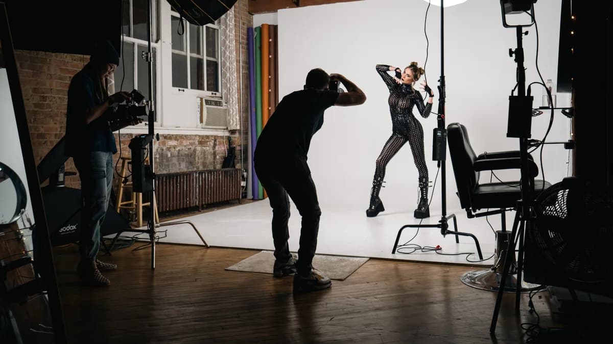 A photographer working a model through looks on a studio set