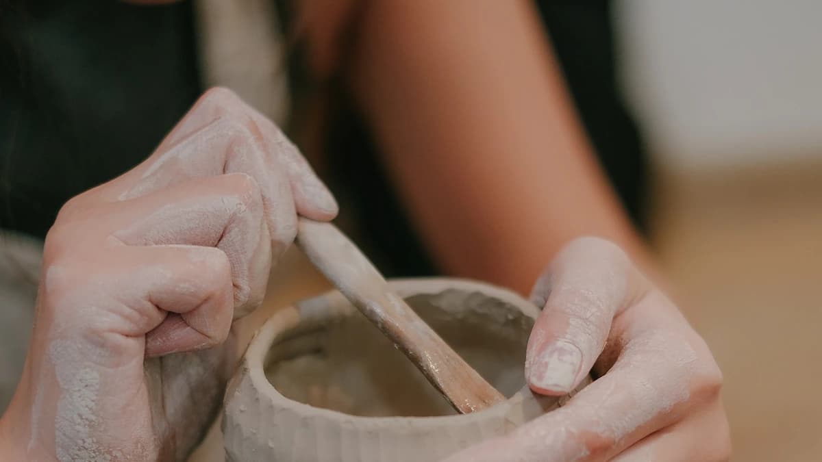 Hands shaping a clay bowl on a potter's wheel