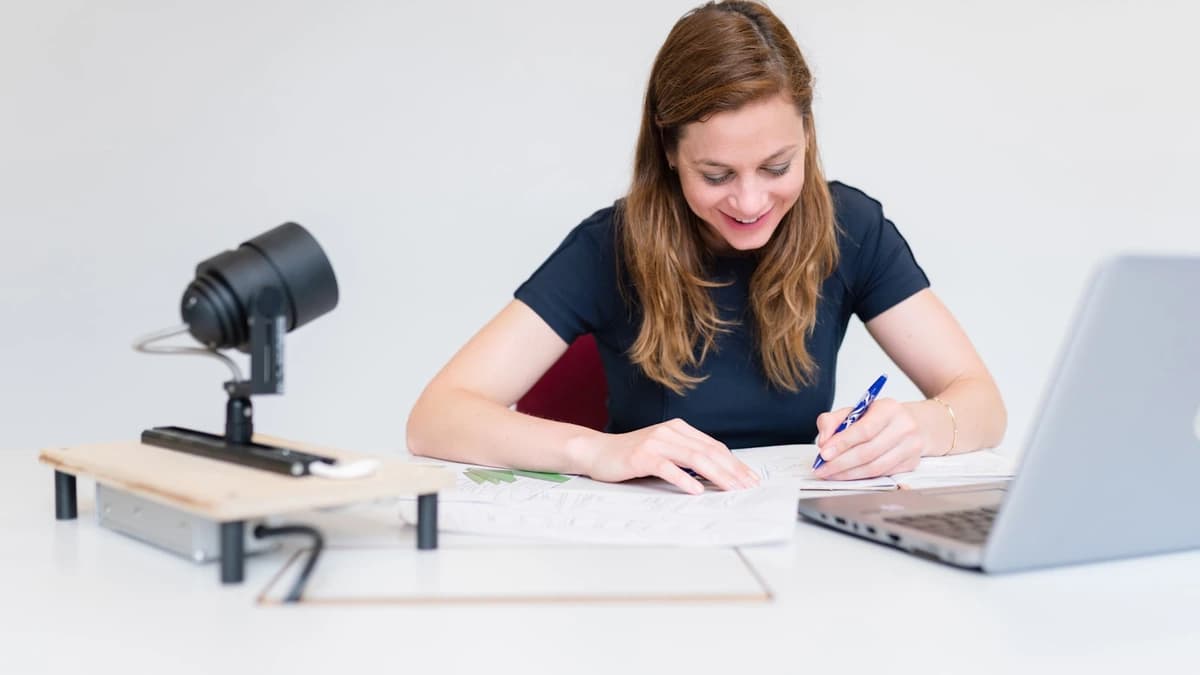 A writer drafting an issue beside an open laptop