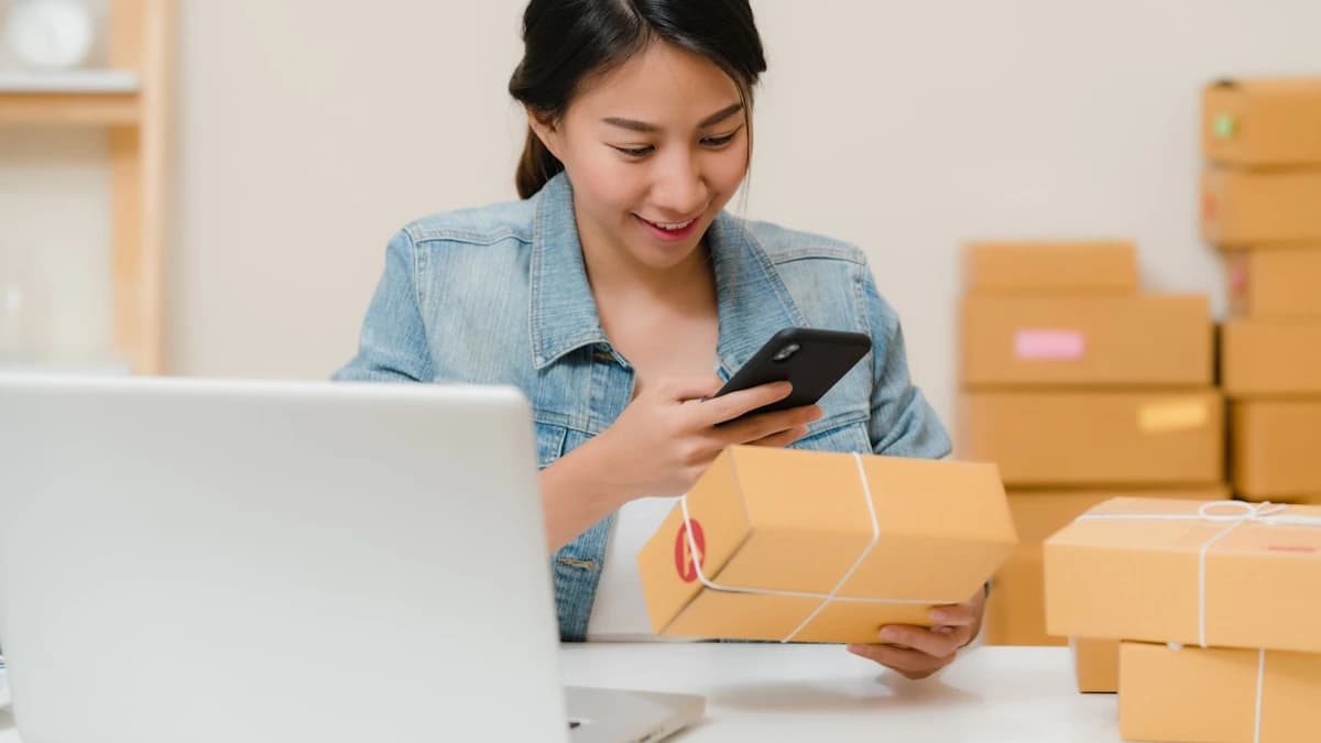 Vorapix use case — an online shop seller checking an order on her phone beside a laptop and stacked parcels