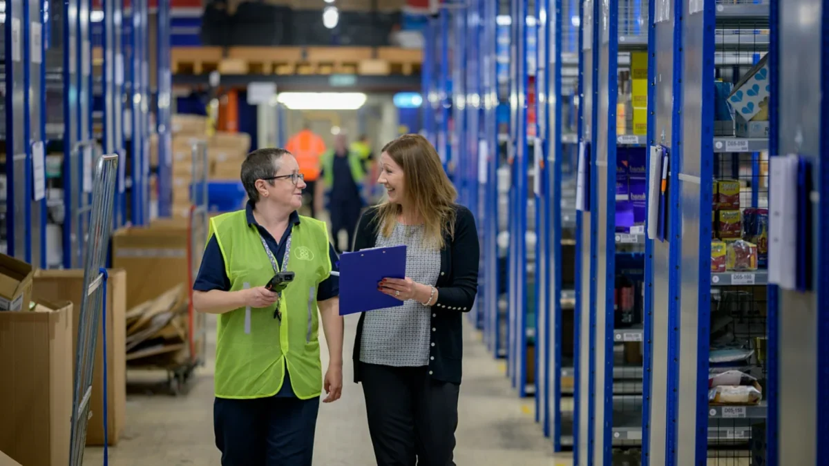 Two sellers checking cartons on warehouse shelving