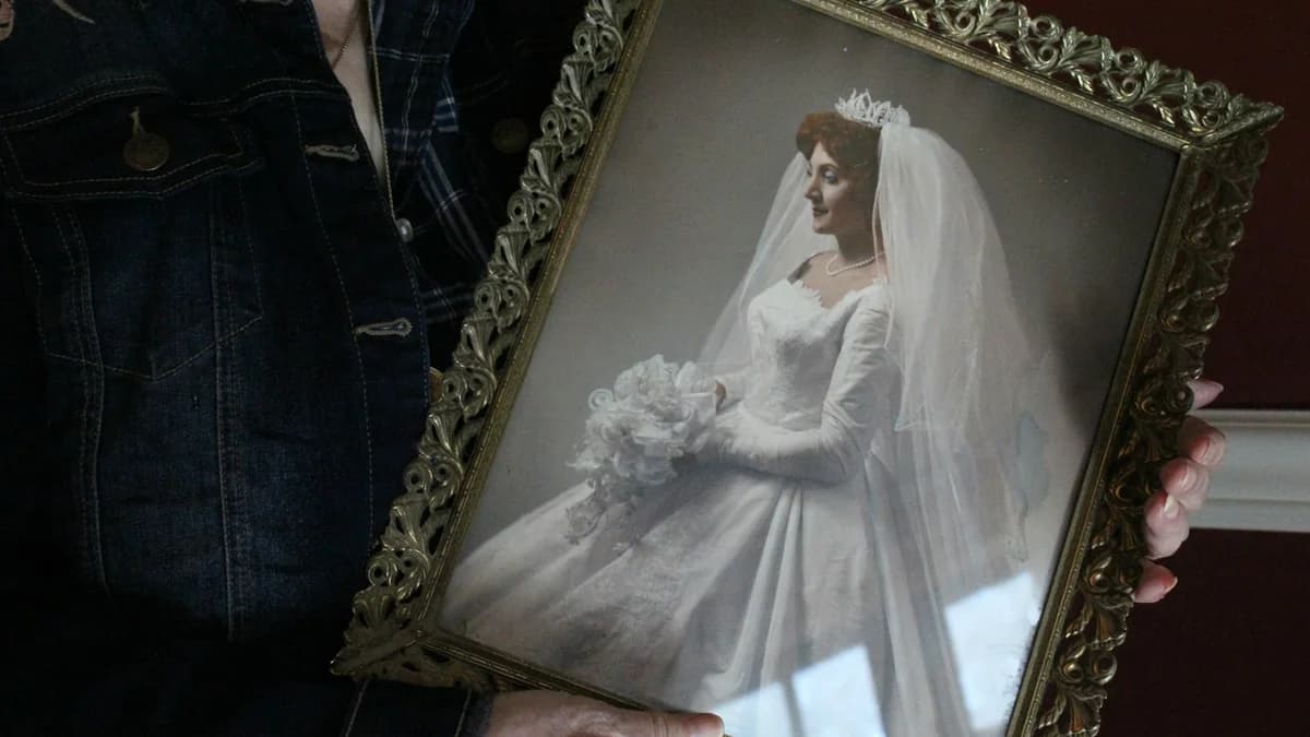 A woman holding a small framed wedding portrait