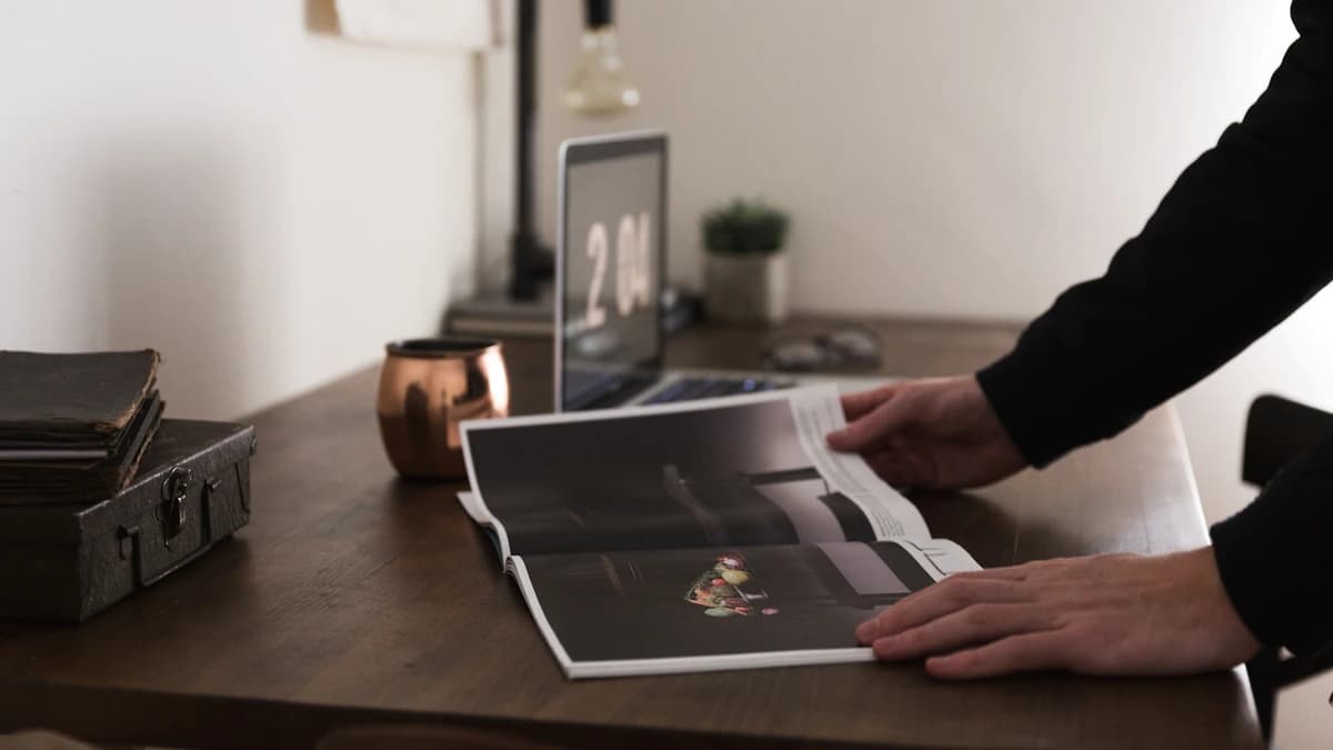 Hands over a printed cover proof on a studio table