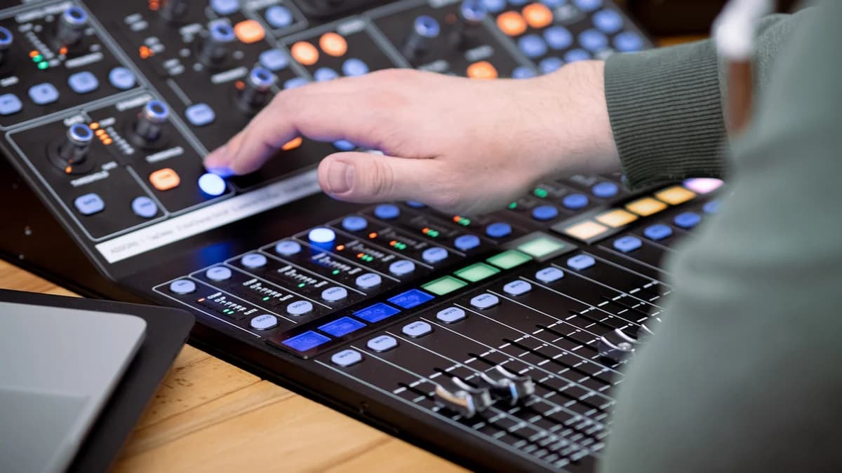 Hands riding faders on a mixing desk mid-pass