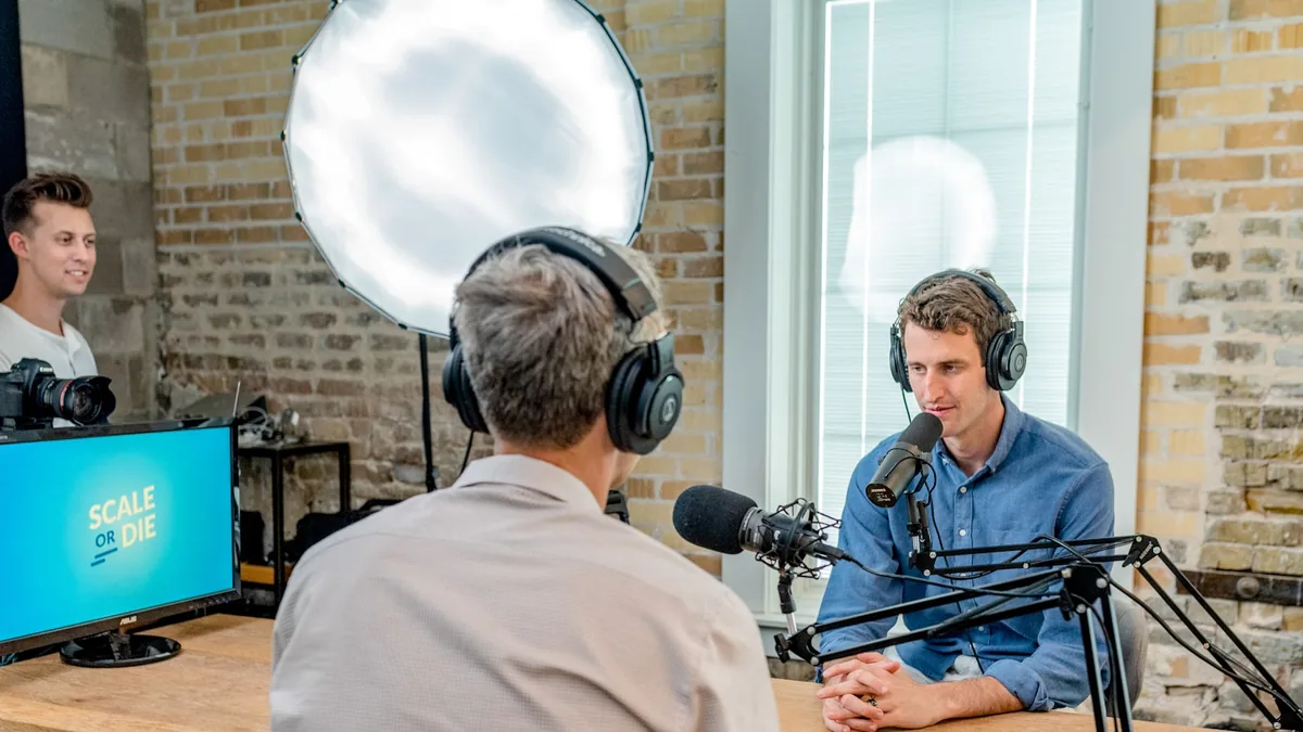 Two hosts recording across a podcast table