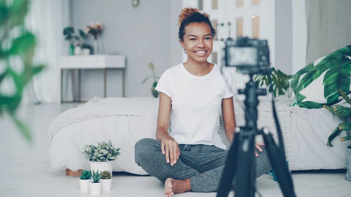 A creator filming herself on a tripod camera at home