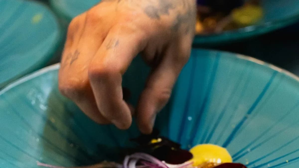 A chef finishing a plate with edible flowers