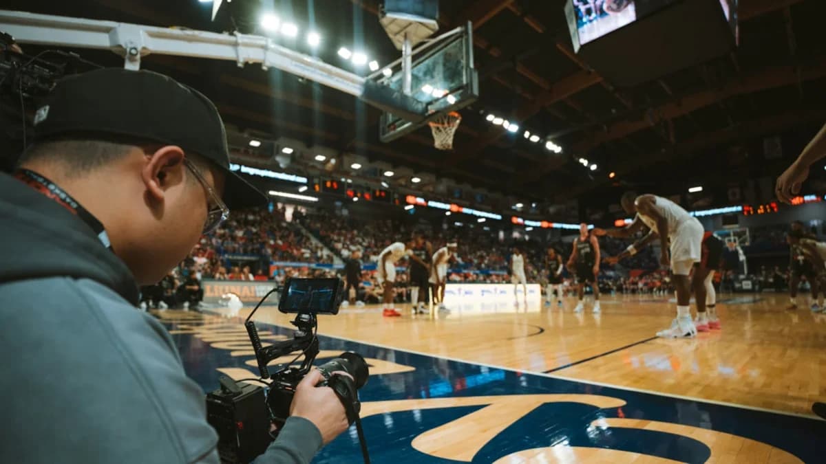 A videographer filming a basketball game courtside